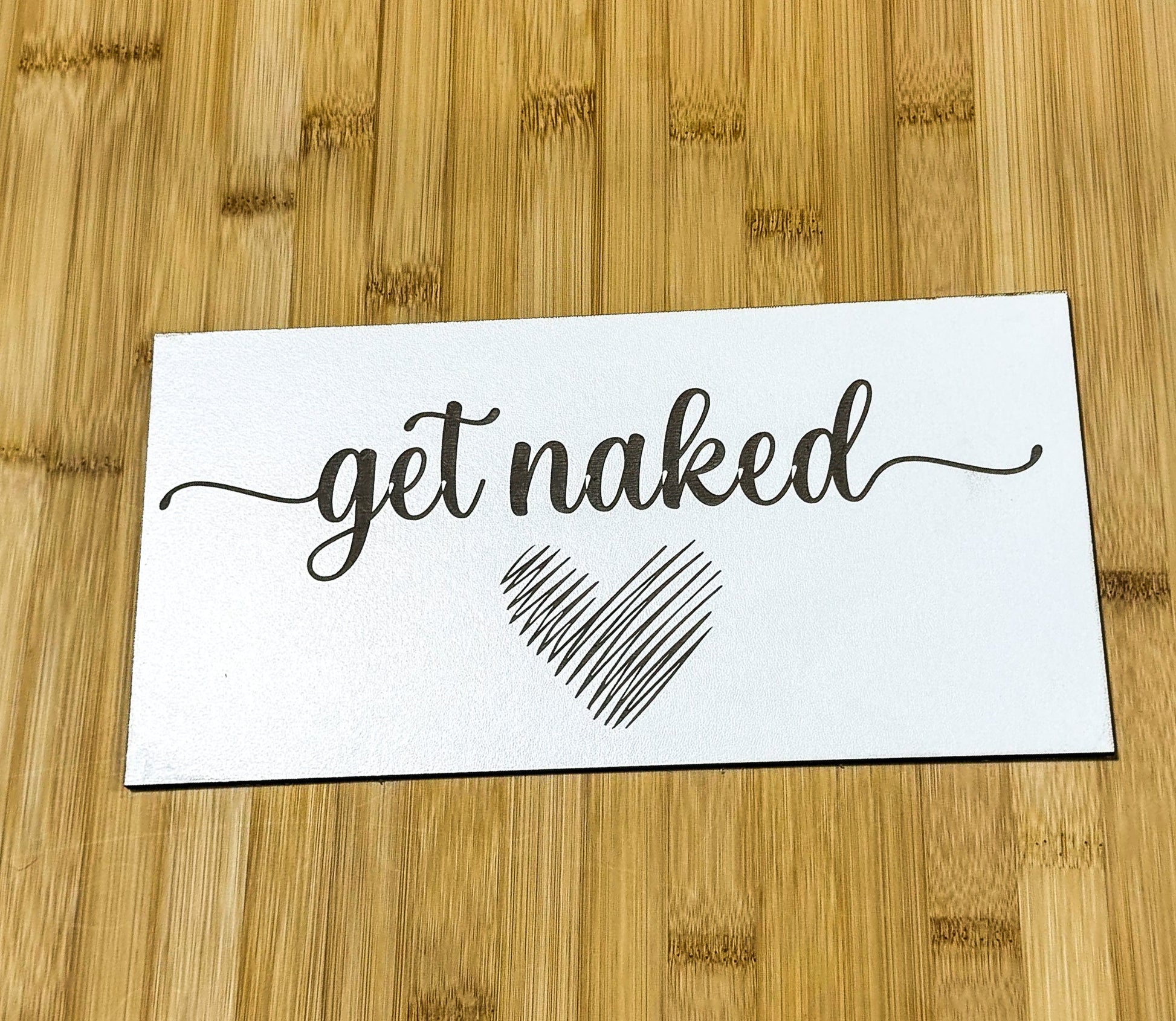 a sticker that says get naked on a wooden surface