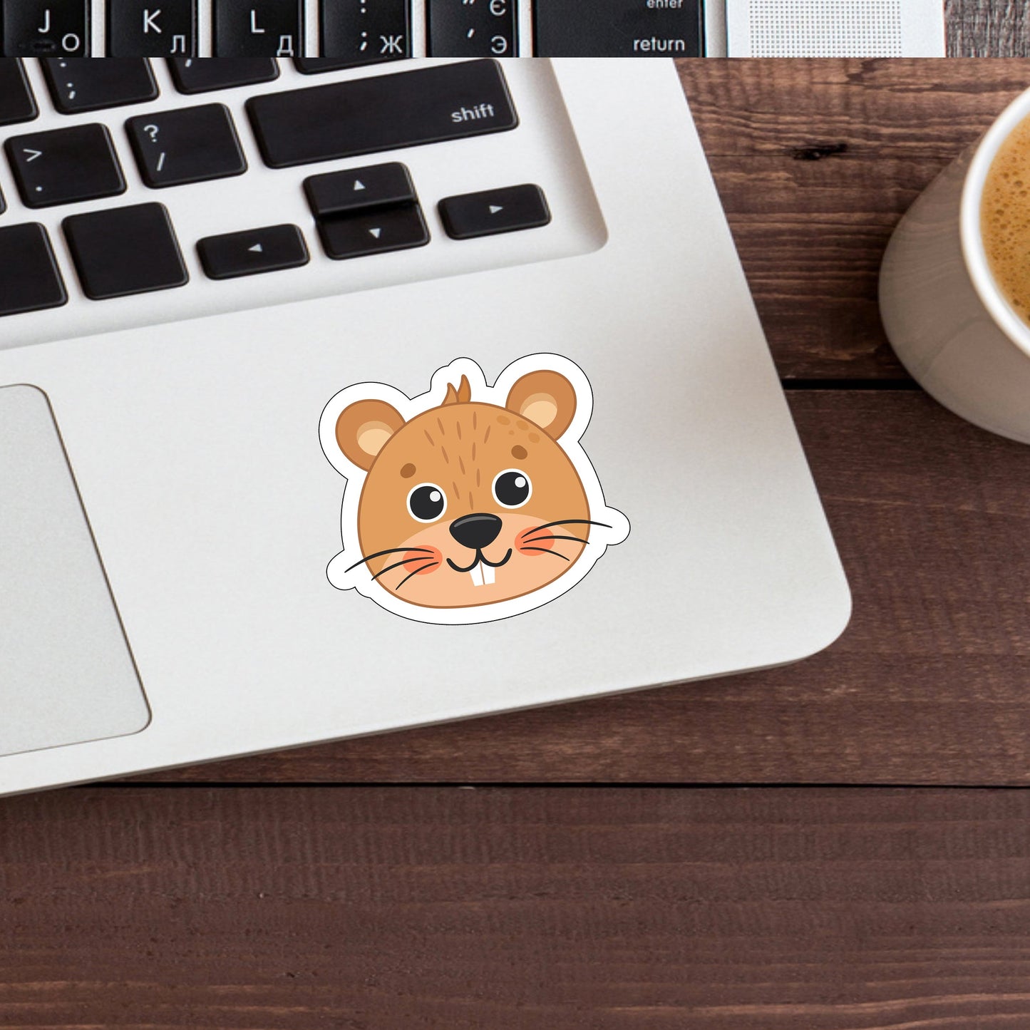 a cup of coffee next to a laptop with a sticker of a mouse