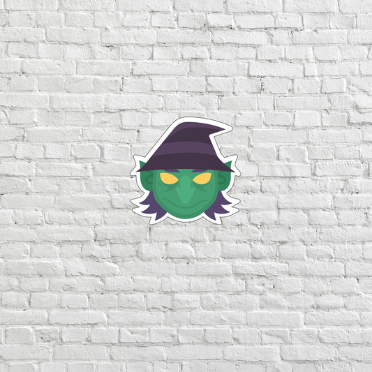 a brick wall with a sticker of a green creature wearing a witches hat